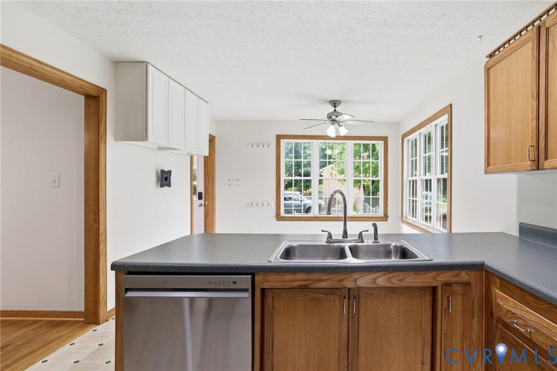Stainless steel double basin sink with a gooseneck faucet, set into a dark countertop
