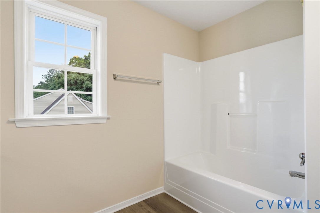 6412 Autumn Mist Way, Chesterfield, VA 23832 Bright bathroom featuring a single-hung window with grilles, a white fiberglass tub/shower combination, polished chrome fixtures, and wood-finish flooring