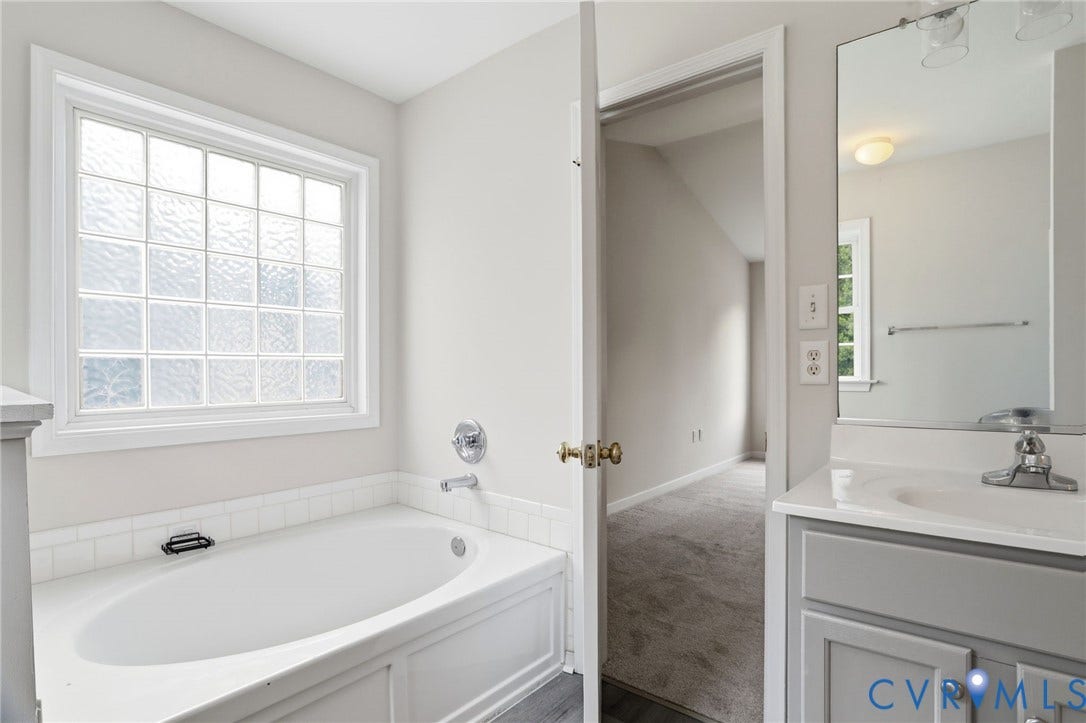 6412 Autumn Mist Way, Chesterfield, VA 23832 Soaking tub with a large glass block window, chrome fixtures, and a white tile surround