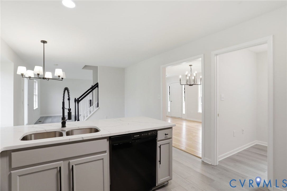 6412 Autumn Mist Way, Chesterfield, VA 23832 Kitchen island featuring a dual-basin stainless steel sink, black gooseneck faucet, light-toned countertop, and light gray cabinetry
