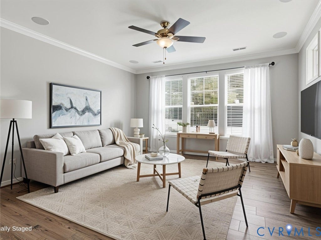 17431 Memorial Tournament Drive, Wynstone Park, Moseley, VA 23120 The sun-filled living room features luxury vinyl plank flooring, built-in surround sound speakers, elegant crown molding, and a ceiling fan, creating a warm and inviting space for everyday living or entertaining