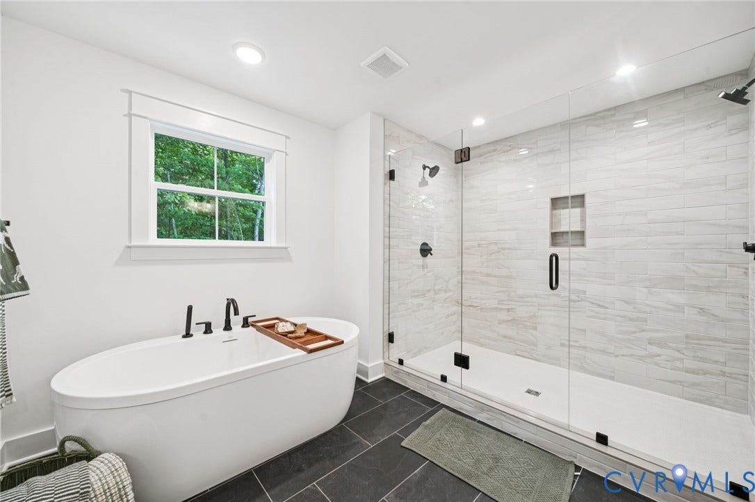 9156 Terroir Lane, Viniterra Villas, New Kent, VA 23124 Freestanding oval soaking tub with matte black fixtures, set against dark tile flooring