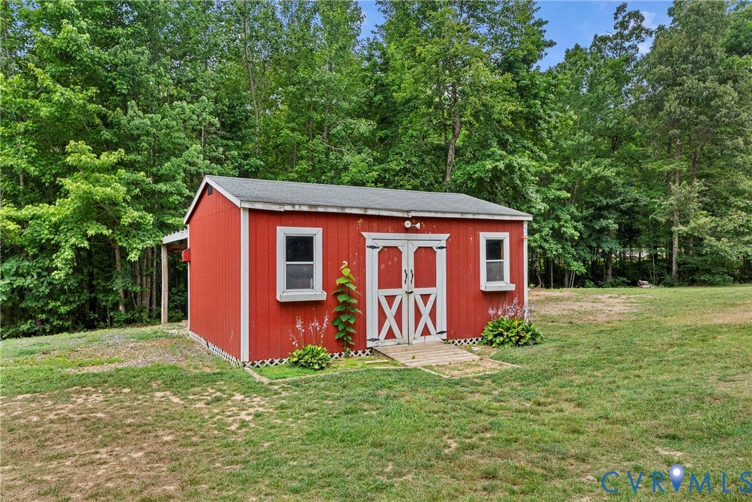 4106 S Spotswood Trail, Trevilians, Louisa, VA 22942 Red exterior shed featuring white trim, double crossbuck doors, a small wooden entry deck, and two windows with white sills