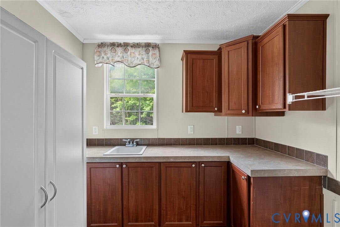 4106 S Spotswood Trail, Trevilians, Louisa, VA 22942 Functional utility area featuring a built-in sink, abundant cabinetry, a window, and a clothes drying rack
