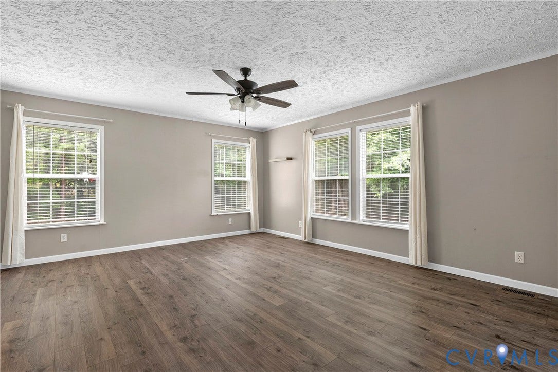 4106 S Spotswood Trail, Trevilians, Louisa, VA 22942 Spacious room featuring wood-finish flooring, a ceiling fan with light fixture, four windows with blinds, and neutral wall paint