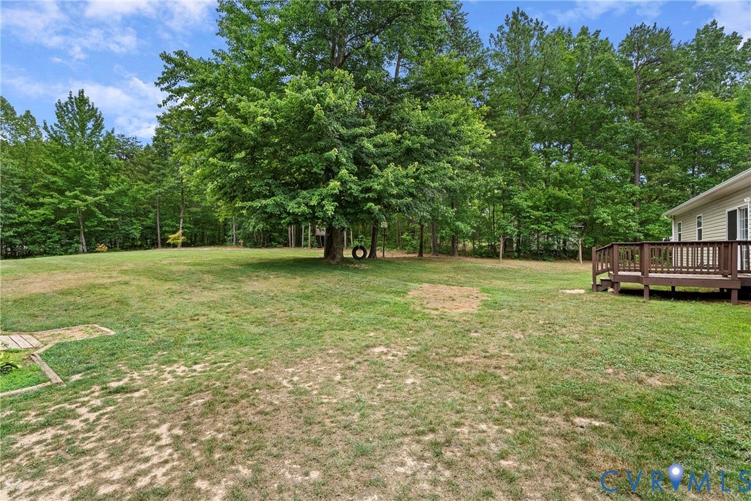 4106 S Spotswood Trail, Trevilians, Louisa, VA 22942 Expansive green space featuring a large wooden deck, mature trees, and a tire swing