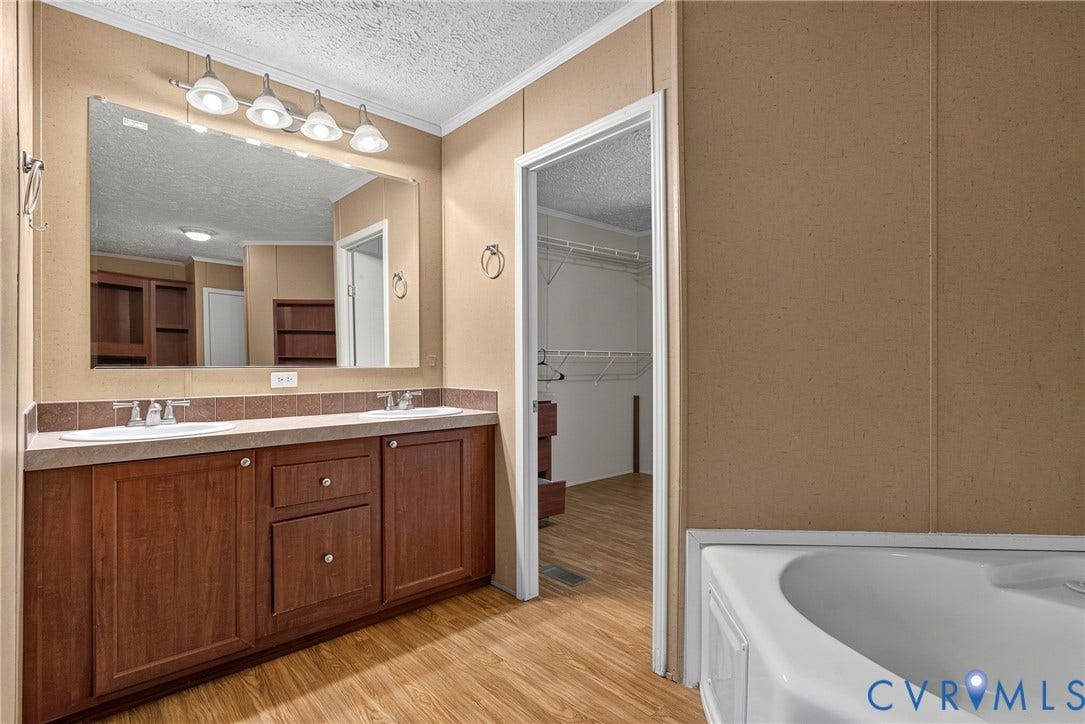 4106 S Spotswood Trail, Trevilians, Louisa, VA 22942 Bathroom featuring a double vanity with two undermount sinks, wood-finish cabinetry, and a full-width mirror with overhead lighting