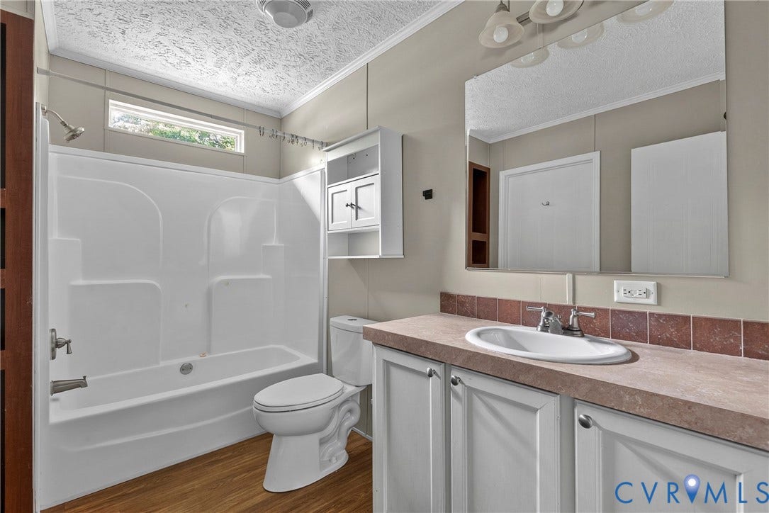 4106 S Spotswood Trail, Trevilians, Louisa, VA 22942 Bathroom featuring a white tub/shower combination, wood-finish flooring, a white toilet, and a vanity with an integrated sink and base cabinetry
