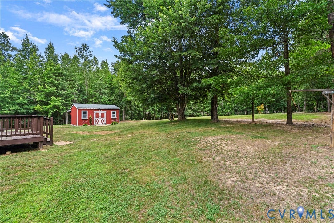 4106 S Spotswood Trail, Trevilians, Louisa, VA 22942 Expansive backyard featuring a red storage shed with white trim, a dark wood-tone deck, and mature trees