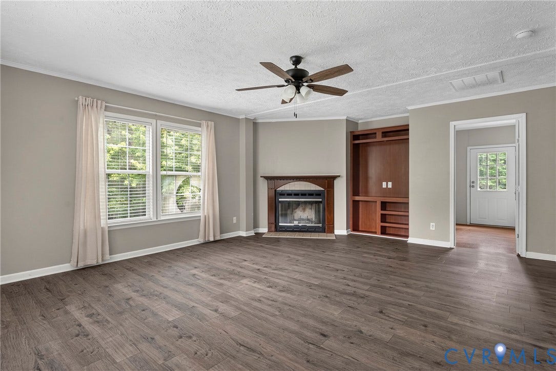 4106 S Spotswood Trail, Trevilians, Louisa, VA 22942 Spacious living area featuring wood-finish flooring, a corner fireplace with a wooden mantel, and a built-in entertainment center