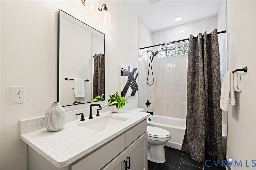 8919 Rustic Road, Richmond, VA 23235 1st floor full bathroom. Modern bathroom featuring a single vanity with a quartz-finish countertop and an integrated sink, matte black faucet, and a black-framed rectangular mirror