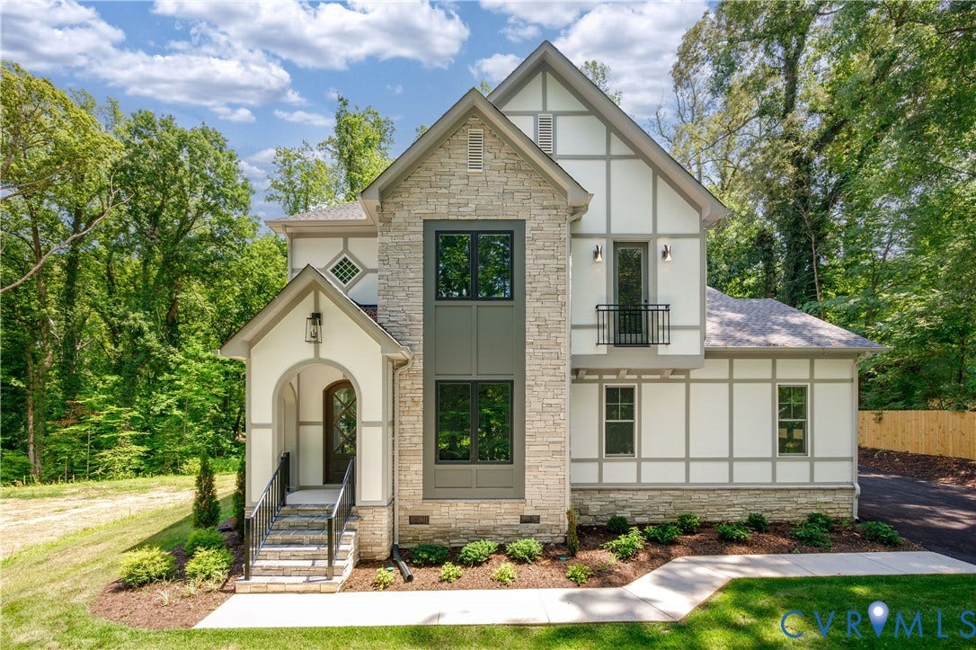 8919 Rustic Road, Richmond, VA 23235 Stone and Tudor-style exterior featuring a covered arched entry, black-framed windows, and a second-story Juliet balcony
