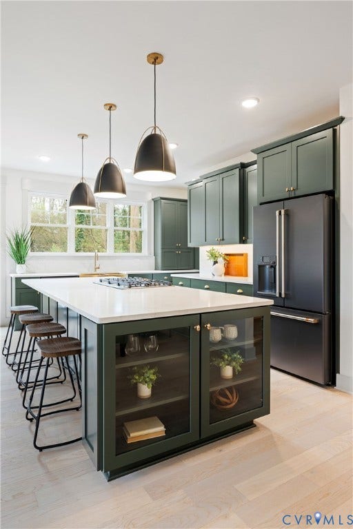 8919 Rustic Road, Richmond, VA 23235 Kitchen featuring dark green cabinetry, a central island with a built-in cooktop, light wood-finish flooring, and black appliances