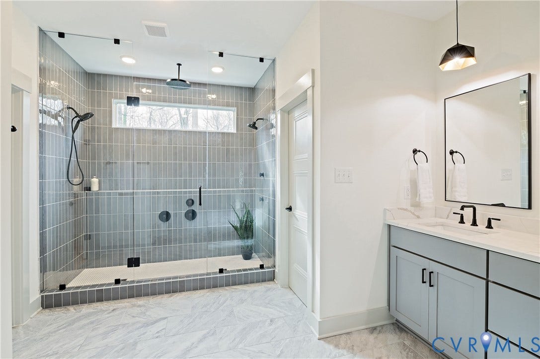 8919 Rustic Road, Richmond, VA 23235 Spacious walk-in shower featuring glass enclosure, vertical subway tile, dual showerheads, and a linear transom window