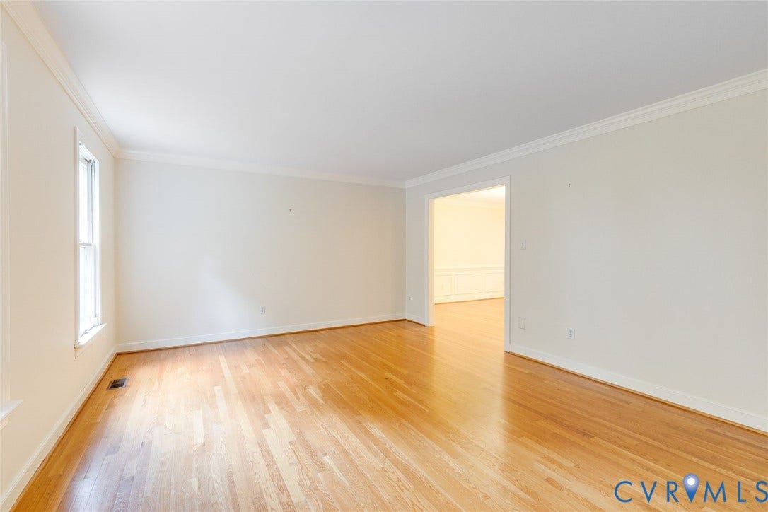 Spacious room with wood-finish flooring, white walls, and crown molding