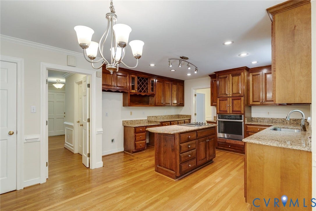 Kitchen with warm wood cabinetry, light-colored countertops, hardwood flooring, a central island, and recessed lighting