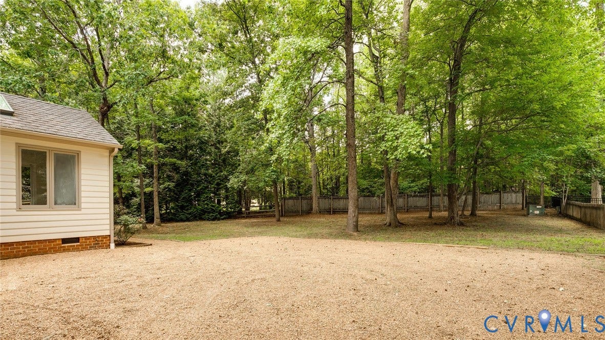 Spacious rear yard with a mix of natural ground cover and grass