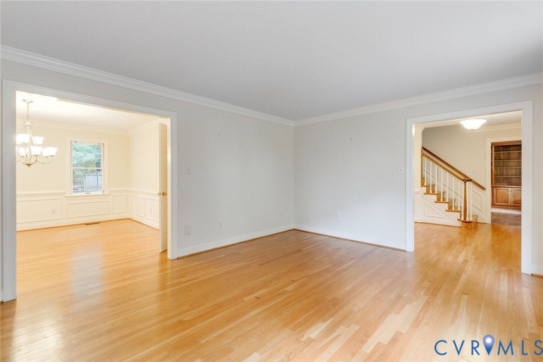 Expansive room with wood-finish flooring, crown molding, and baseboards