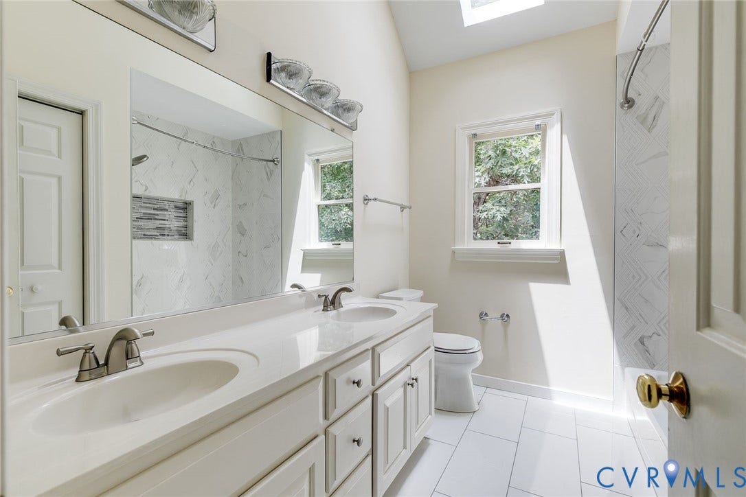 Bright and airy second floor hall bath has been updated with new tile floor and tub surround, double vanity, and fixtures.