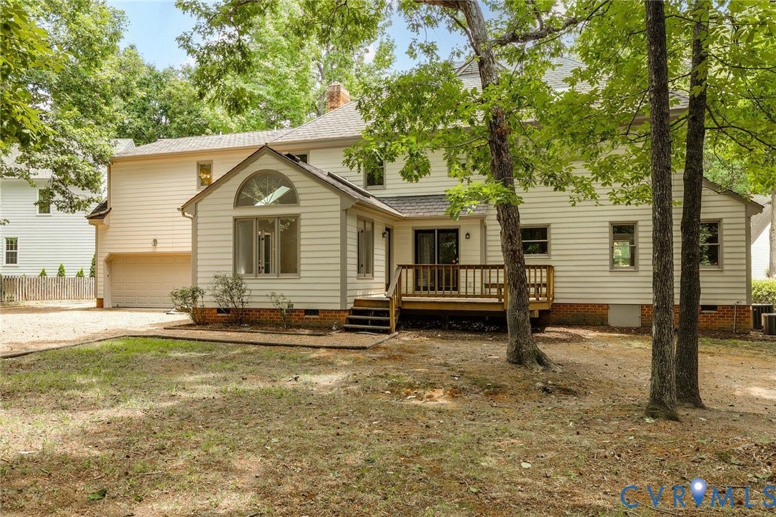 Rear exterior featuring a spacious wooden deck with railings, a prominent arched window, and siding construction
