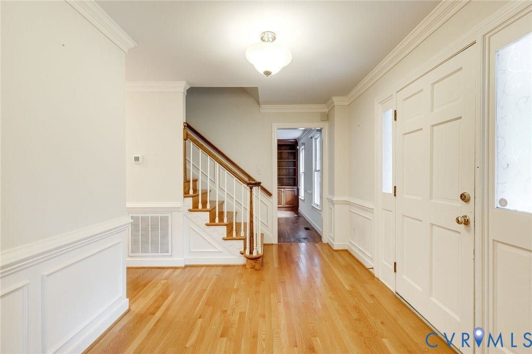 Hardwood flooring extends through the entryway, featuring a paneled front door with sidelights