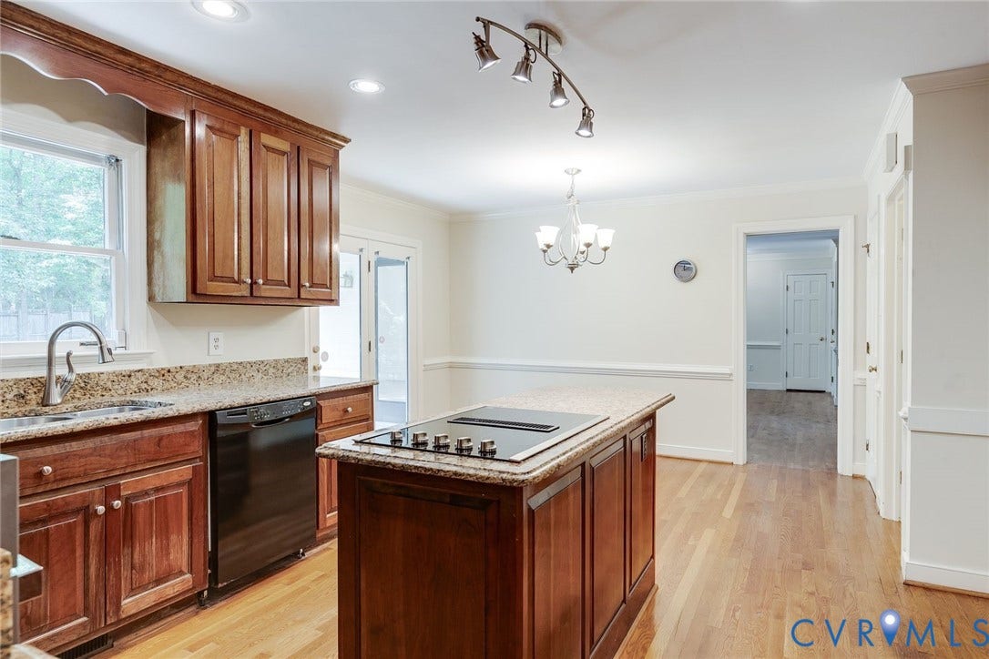 Kitchen featuring wood cabinetry, granite countertops, a built-in cooktop, and hardwood flooring