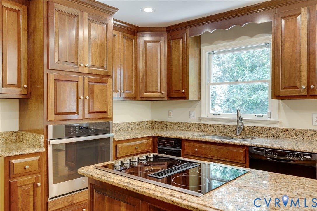 Kitchen featuring wood cabinetry, granite countertops, an integrated cooktop, a built-in wall oven, and a stainless steel sink with a single-handle faucet