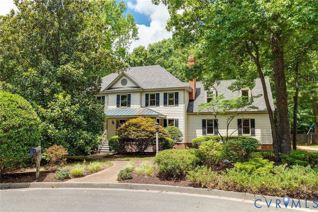 Traditional-style residence featuring light-toned siding, a dark shingle roof, and multiple dormer windows