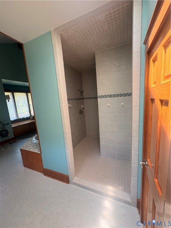 Walk-in shower featuring gray subway tile walls, a mosaic tile floor, and an accent tile band