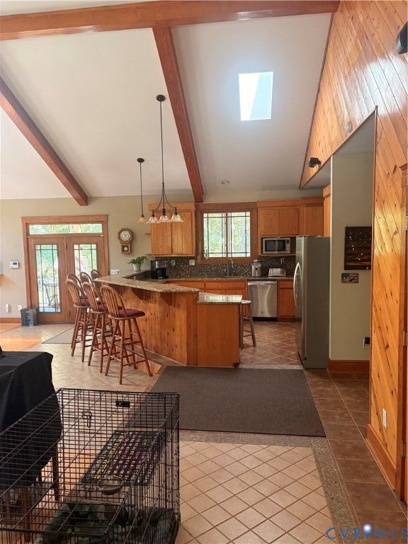 Vaulted ceiling with exposed wood beams and a skylight