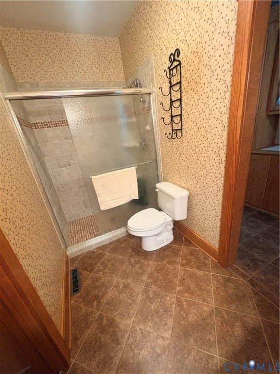 Tiled shower enclosure with sliding glass doors, featuring a decorative accent tile band
