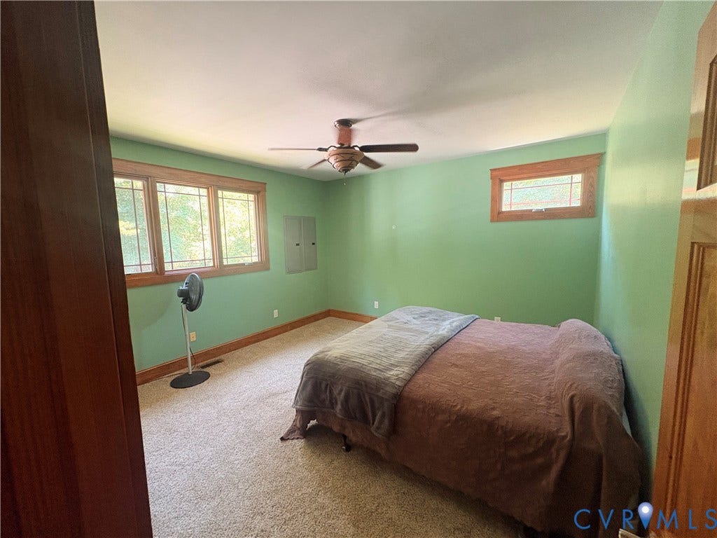 Carpeted room featuring a ceiling fan, a multi-pane window with wood trim, and a smaller horizontal window also with wood trim