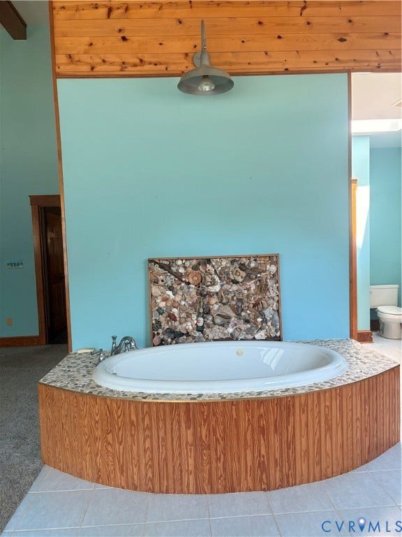 Soaking tub with a pebble tile surround and wood-finish paneling, set against a vibrant accent wall