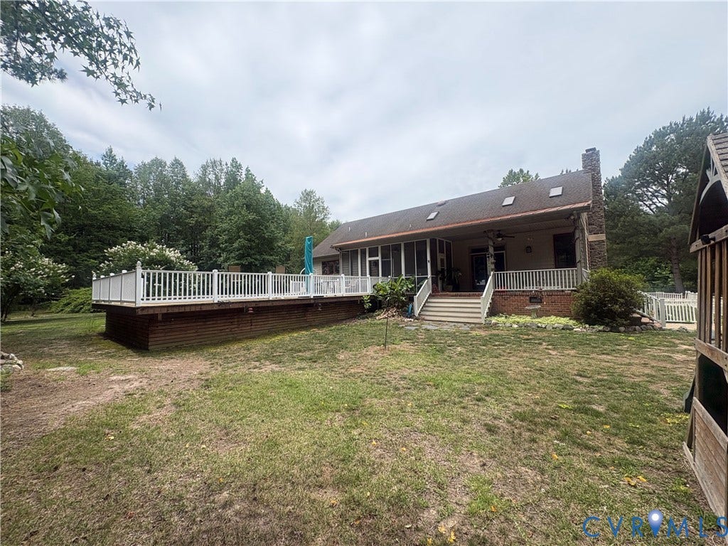 Expansive rear deck with white railings and brick base, featuring multiple levels and direct access to a screened porch