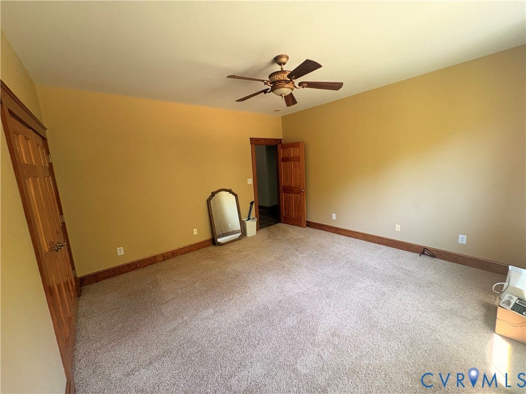 Carpeted room featuring a ceiling fan with integrated lighting, wood trim, and wood-paneled doors