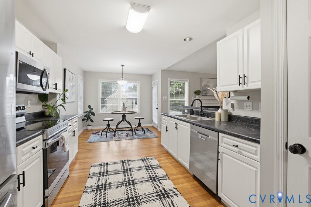3819 Daniels Street, Chesterfield, VA 23831 Kitchen featuring white cabinetry, stainless steel appliances, black countertops, and wood-finish flooring