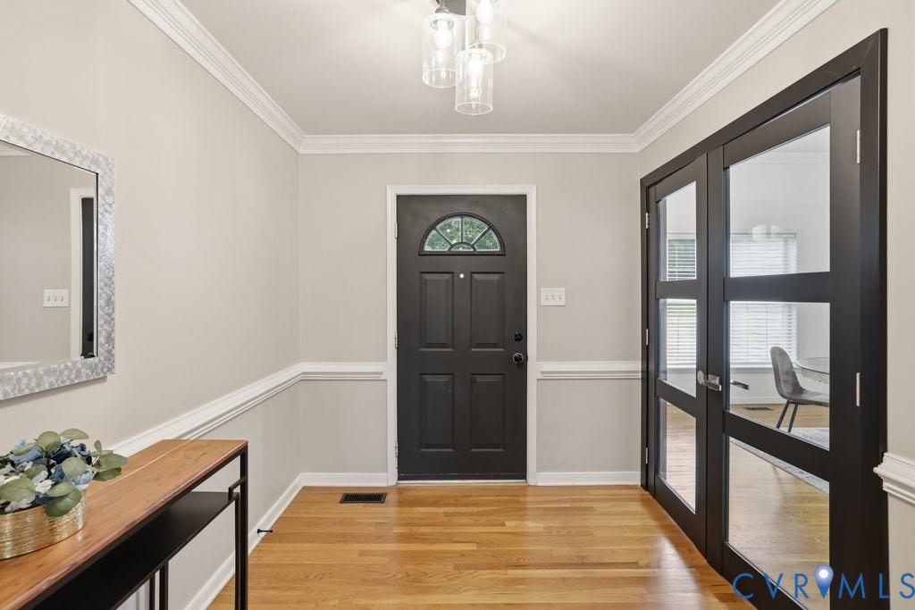 3819 Daniels Street, Chesterfield, VA 23831 Entryway featuring a dark paneled front door with an arched transom window, glass-paneled double doors, wood-finish flooring, crown molding, and chair rail detailing