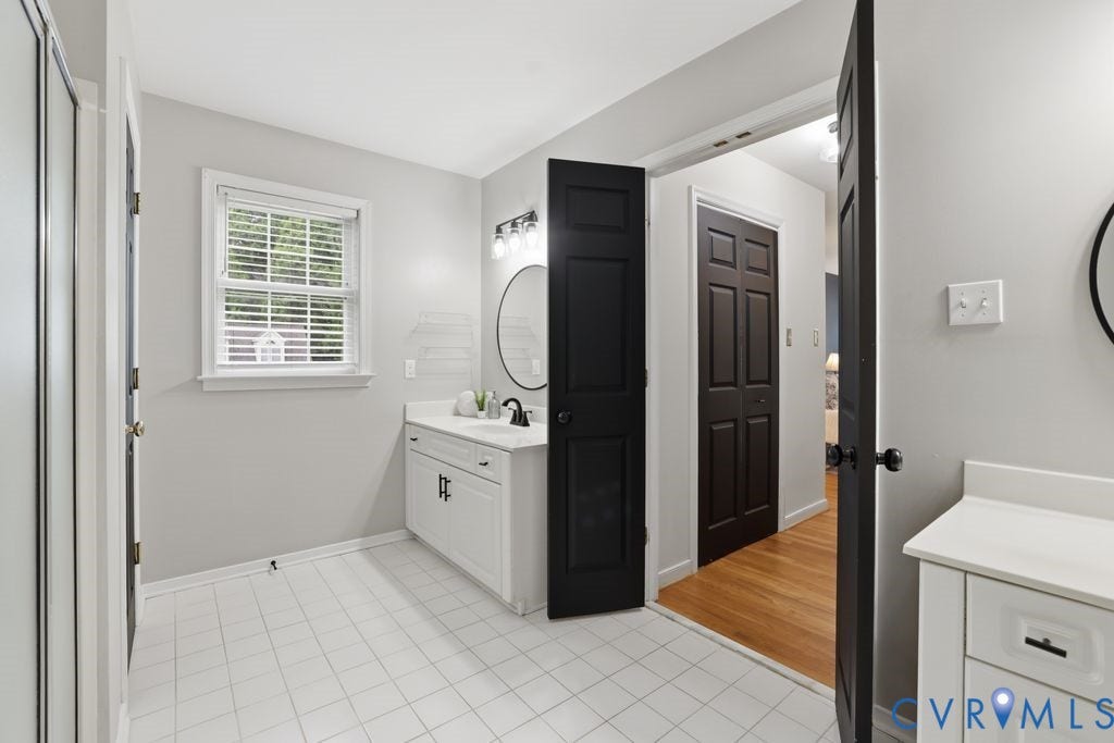 3819 Daniels Street, Chesterfield, VA 23831 Bathroom featuring a white vanity with an undermount sink, a round mirror, and a three-light fixture