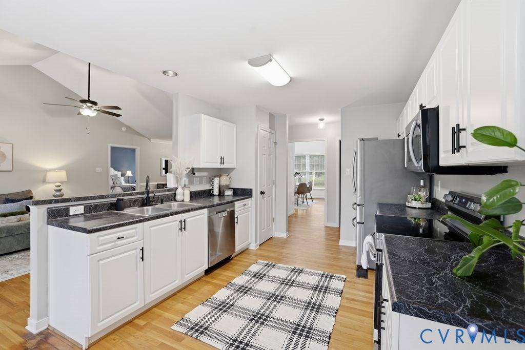 3819 Daniels Street, Chesterfield, VA 23831 Open-concept kitchen featuring white cabinetry, black stone-finish countertops, stainless steel appliances, and wood-finish flooring