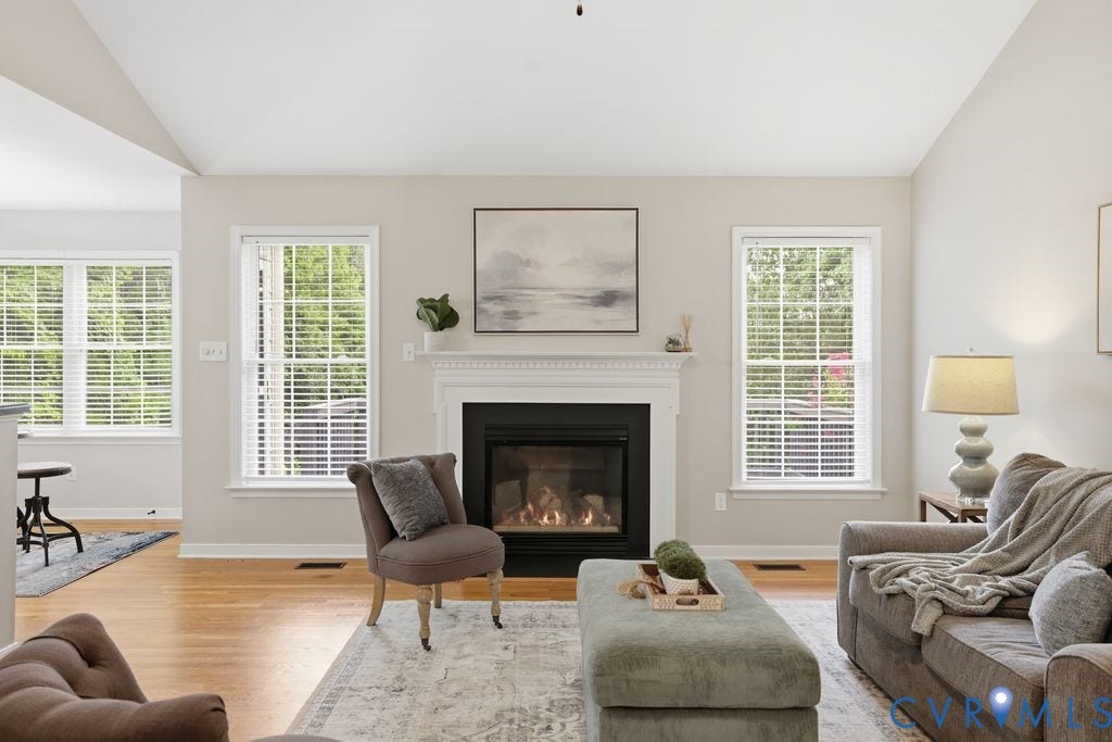 3819 Daniels Street, Chesterfield, VA 23831 Living area featuring a white mantel fireplace, hardwood flooring, and multiple windows with white blinds