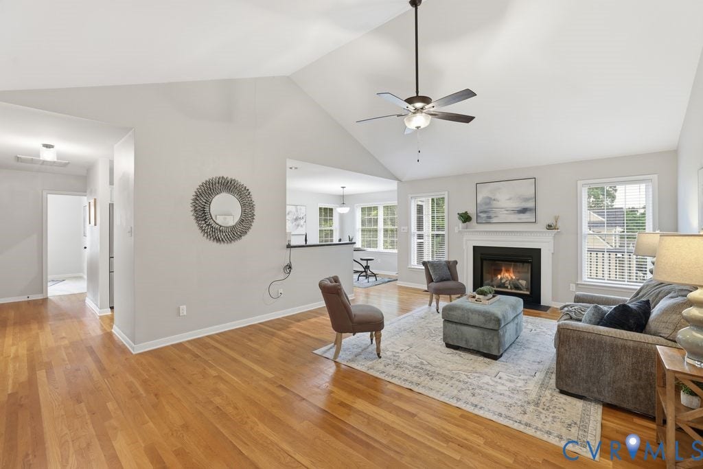 3819 Daniels Street, Chesterfield, VA 23831 Vaulted ceiling living area featuring hardwood flooring, a fireplace with a white mantel, and multiple windows providing natural light