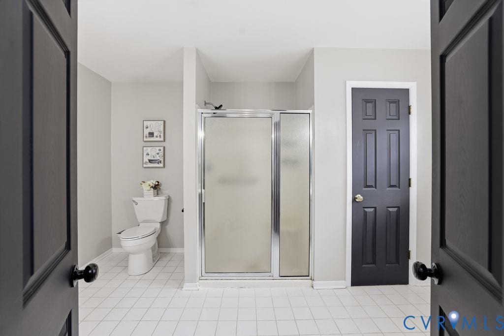 3819 Daniels Street, Chesterfield, VA 23831 Bathroom featuring light gray walls, white floor tiles, a shower with sliding frosted glass doors, and a toilet