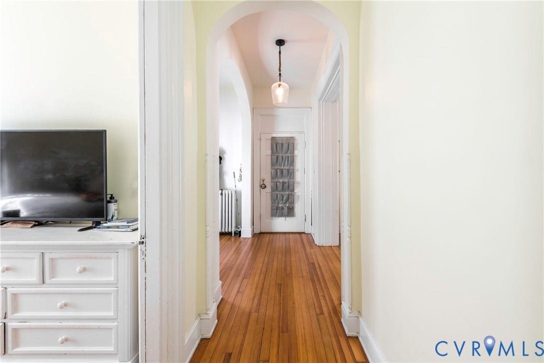 4404 Patterson Avenue, Richmond, VA 23221 Archway entry leading to a hallway with wood-finish flooring, a contemporary pendant light fixture, and classic white trim