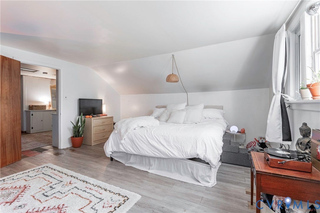 4404 Patterson Avenue, Richmond, VA 23221 Sloped ceiling room featuring wood-finish flooring, a window with natural light, and an open doorway to an adjoining space with built-in cabinetry