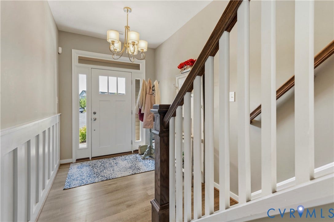 10414 Perennial Drive, Henrico, VA 23233 Entryway featuring a decorative chandelier, white board and batten wall treatment, wood-finish flooring, and a staircase with a dark wood handrail and white balusters