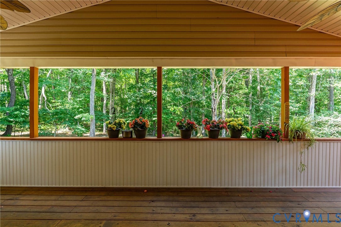 Covered porch featuring wood-finish flooring, beadboard wainscoting, and a slatted ceiling with exposed beams