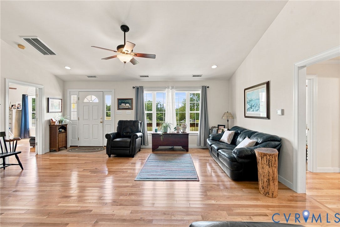 Spacious living area featuring wood-finish flooring, vaulted ceilings, and recessed lighting