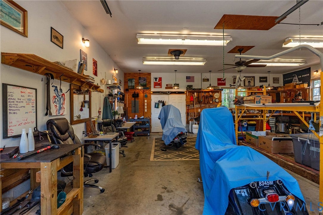 Spacious garage featuring concrete flooring, track lighting, ceiling fans, built-in shelving, and multiple work areas