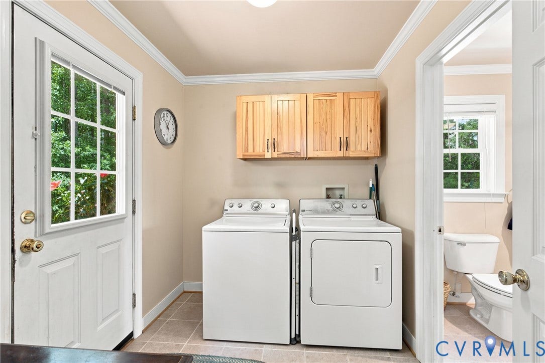 Dedicated utility room featuring light wood cabinetry, tiled flooring, and a windowed exterior door