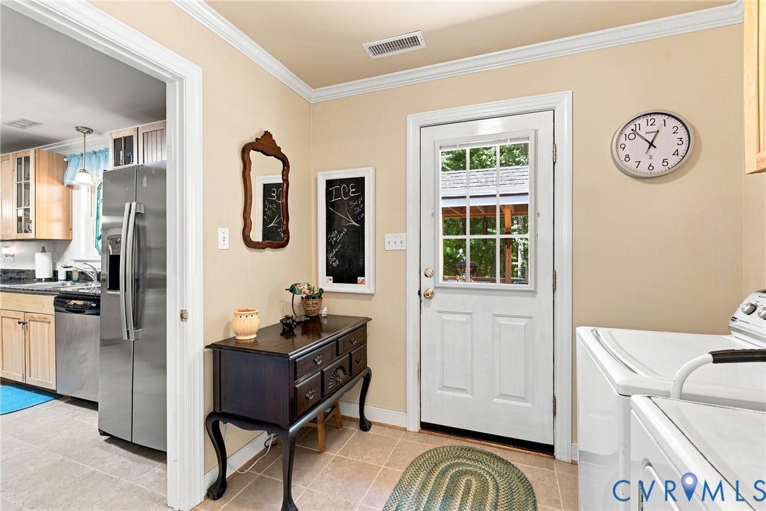 Utility room featuring a paneled exterior door with glass insert, crown molding, and tile flooring